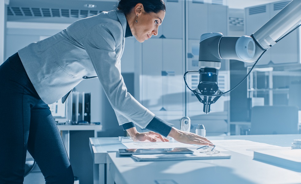 Stylish Female Robotics Engineer Leans on the Table Works with Blueprints, Documents and Tablet Computer, She's Programming Robot Arm Movements Stylish Female Robotics Engineer Leans on the Table Works with Blueprints, Documents and Tablet Computer, She's Programming Robot Arm Movements